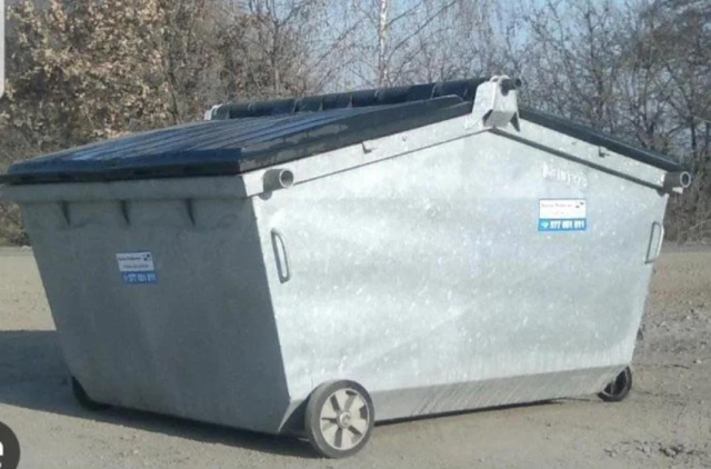 A picture of a grey trash dumpster with wheels, which vaguely looks like Tesla's Cybertruck.