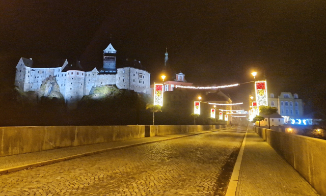 Loketský most do centra s výzdobou a osvíceným hradem v pozadí 
