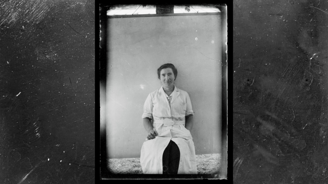 photo of Marguerite Perey in her long lab coat. She is a white woman with dark hair.