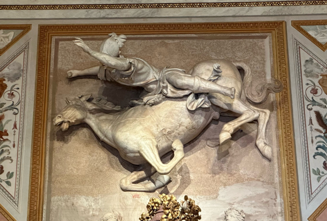 A life size horse tripping and spilling a guy, mounted on the wall above an ornate fireplace (not shown)