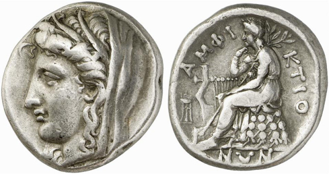 "Head of Demeter to left, wearing wreath of wheat ears and veil ΑΜΦΙ-ΚΤΙΟ-ΝΩΝ, Apollo Pythios, laureate and wearing a chiton, seated left on an omphalos draped with his himation and covered with a network of knotted woolen cords. His right elbow is propped on his kithara, he rests his chin on his right hand and he holds a long laurel branch over his shoulder with his left hand... In the field to left, tripod."

Classical Numismatic Group, Inc. cngcoins.com, CC BY-SA 2.5, via Wikimedia Commons.
