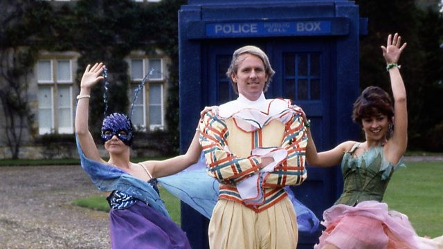 The Fifth Doctor, dressed as a Harlequin, standing in front of the TARDIS