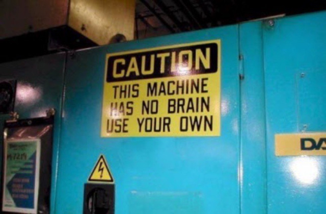 Sign on large industrial device saying "caution, this machine has no brain use your own"