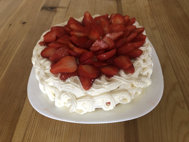 Un pastel de fresas con crema sobre la mesa de madera.