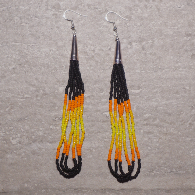 Black, orange, and yellow Native beaded loop earrings on a stone background