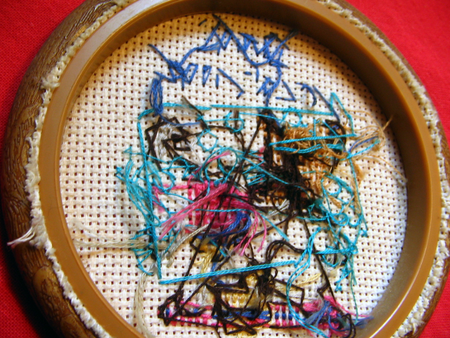 The previous crossstitching work (with the bear) flipped over, and so now it shows the chaotic mess of strings in the back that were used to make the art