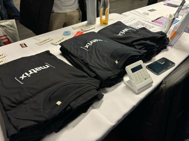 A picture of t-shirts on a booth table with a credit card reader in front of them