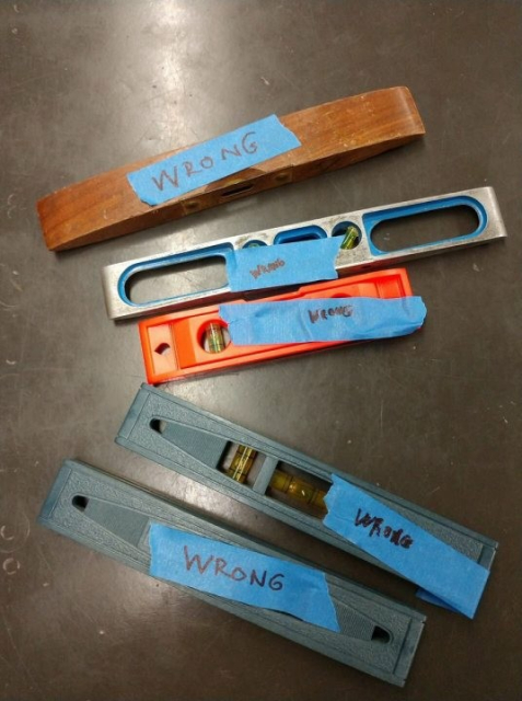 A picture of five builders levels, each marked with a blue sticker worded "WRONG"