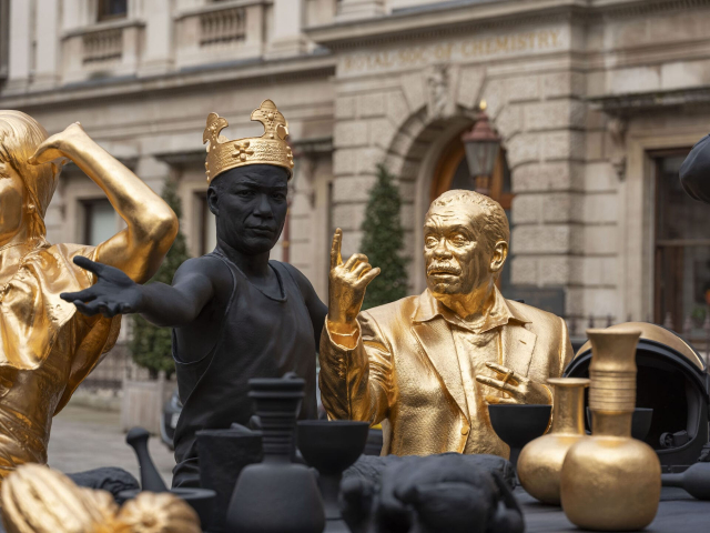 In bronze, black patina, and gold leaf, two Black historical figures gesture in an animated way, recreating the Renaissance painting.