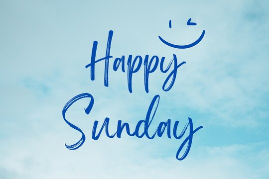 An image that has a blue sky with clouds as the background and the words Happy Sunday written in a thin blue, script like font with a little smiley face above it.
