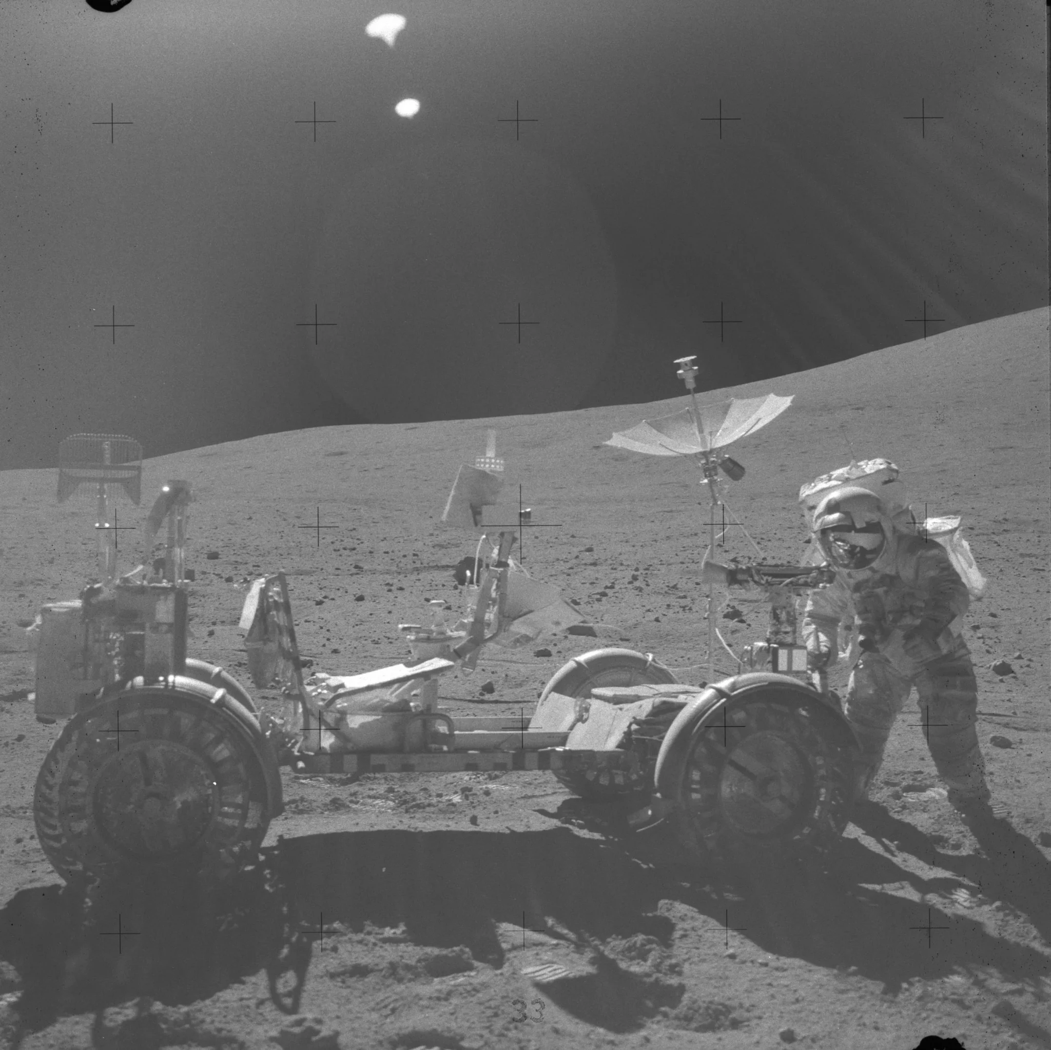 A side-profile photo of the lunar rover from Apollo 16. John Young stands at the front of the vehicle, to the right of the photo frame. He is using the lunar dust brush to clean regolith off of the vehicle. https://www.nasa.gov/history/alsj/picture.html
