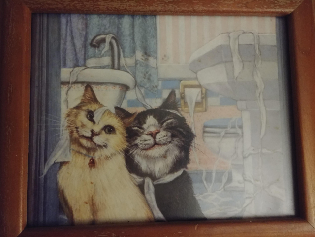 This is actually a pretty nice painting, and I used to keep it in the bathroom.

On the left is a long hair beige cat, with a bell around it's neck. The cat beside it has a huge grin and smiley eyes, and they rubbing heads.

In the background is a shower curtain on the left, and a sink and tub absolutely covered in toilet paper.

I believe this is the most realistic piece of cat art I may have, even though the painting itself is a bit cartoonish.