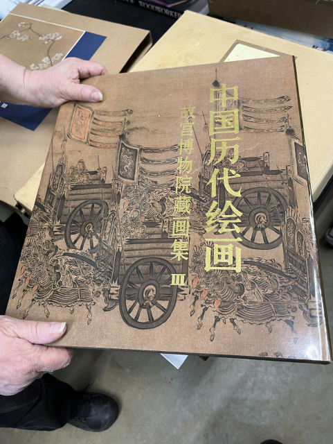 The cover of an art book, on a table with other art books; the text is in Chinese. 