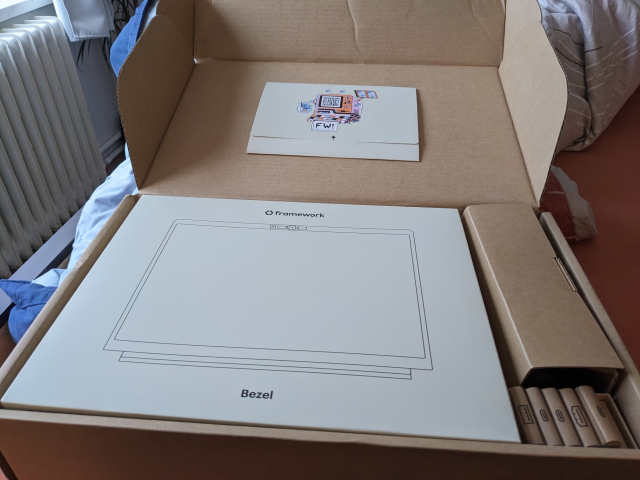 Opened box, containing components in paper boxes, and a welcoming letter in the lid of the box.