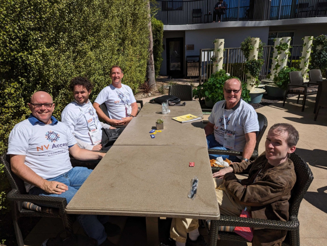 Quentin, Sean, Gerald, James and Mick sitting around a table in the sun.