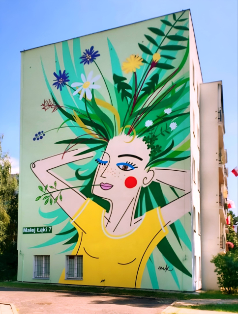 Streetartwall. On the outside wall of a four-storey modern apartment block is a mural of a girl with a flowering meadow in her hair. The background is light green. A young woman in a yellow T-shirt holds her arms up and reaches into her hair. But instead of hair, green blades of grass and colorful wildflowers are growing there. Her face is somewhat abstract. She has one eye closed, a red cheek and a blade of grass in the corner of her large red mouth.
Info: The street name is written large on the wall of the house and translates as "small meadow".