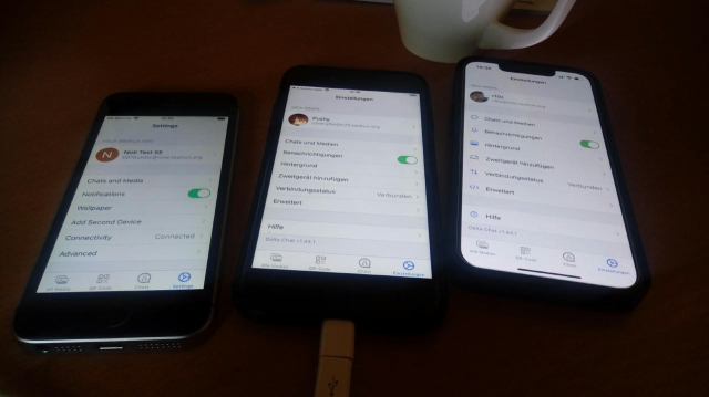 three iPhones lying on a table, showing settings screen of Delta Chat 1.44.1 each