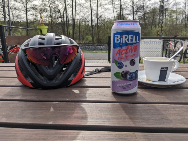 Zátiší s cyklistickou helmou a plechovkou Birella.
Vpravo šálek kávy.