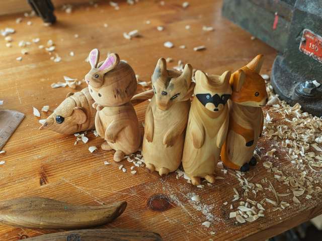 A group of woodcarved critters : a elephant eared shrew, a weird monster having a plump rabbit as its head, a gargoyle with three eyes, a standing racoon and a standing fox