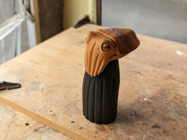 A woodcarved cuttlefish wearing a black dress