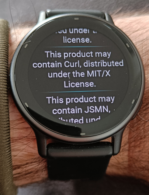 A Garmin watch on a hairy wrist, the former displaying the message: "This product may contain Curl, distributed under the MIT/X License."