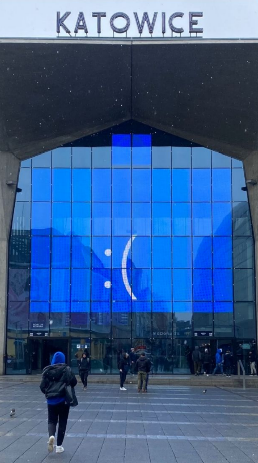 the ":(" from the windows bluescreen, appearing on the giant display screen on the katowice train station
