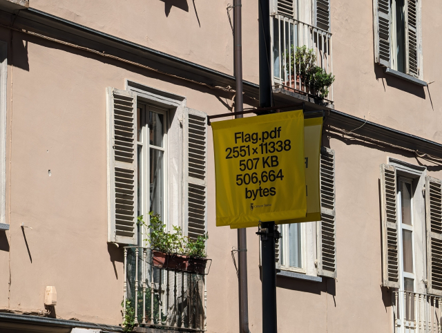 A yellow banner on a lamppost. In block sans serif caps, it reads: 

FLAG.PDF
2551X11338
507 KB
506,664 bytes