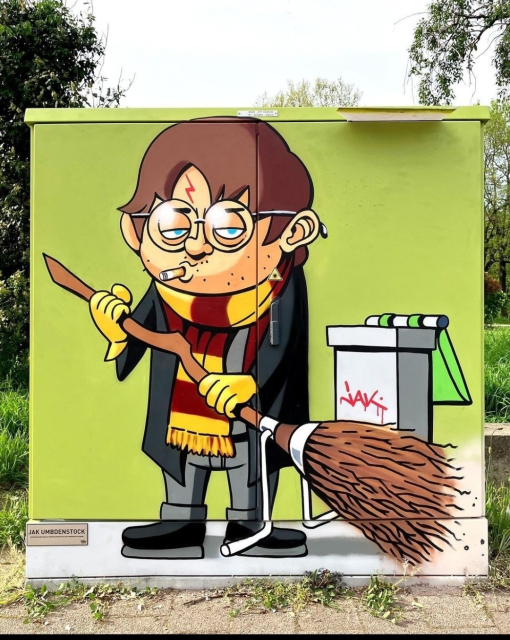 Streetartwall. On a formerly gray 
power supply box, a picture of the wizard's apprentice Harry Potter has been painted in comic style. Harry has short brown hair, his round nickel glasses, a long green jacket, his red and yellow woollen scarf, gray trousers and black shoes. He has a cigarette in the corner of his mouth, is unshaven and sweeps the street with his magic broom. There is an open dustbin next to him.  Now it's finally clear what has become of Harry Potter. 
Info: Jak Umbdenstock is a young artist from Strasbourg, illustrator and press illustrator. Jak's work has many facets and mixes poignancy with provocation. His illustrations are sometimes critical, sometimes full of satire and (often black) humor.

