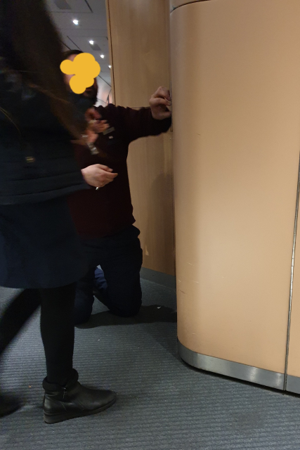 Ein Bahn Mitarbeiter kniet im Zug und versucht eine Tür zu öffnen