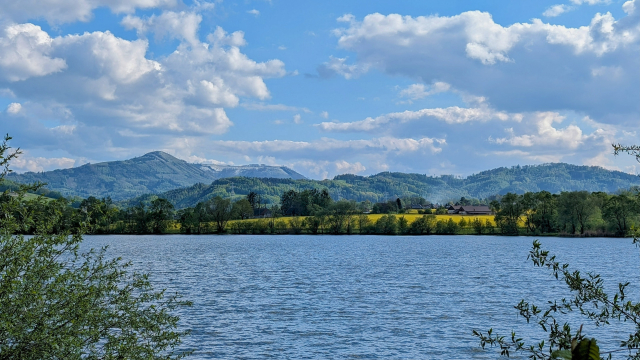 Pohled na krajinu, v popředí vodní hladina, v pozadí jsou hřebeny hor s dominantním Ondřejníkem.