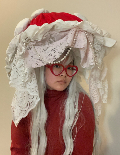 Front view of the mushroom hat. Pearls line the front lace. It sort of looks like I'm surrounded by a lace picture frame lol. I have silver hair and red heart glasses.