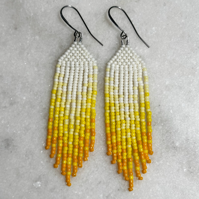 White to yellow ombre Native beaded fringe earrings on a marble background