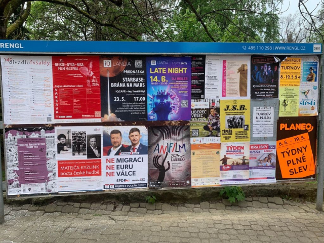 Plakatovaci plocha s ruznymi kulturnimi akcemi a klauny.