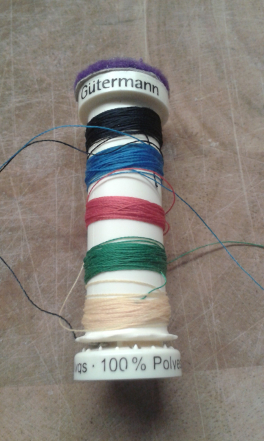 A guterman cotton reel, with 5 different colours of thread wound onto it.