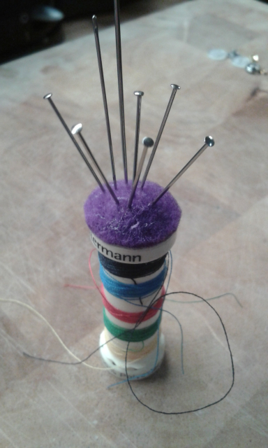 The top of the cotton reel with a little felt pad glued to it, acting as a pin cushion.