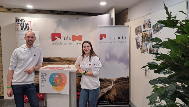 Arne and Tabea from Tuta stand smiling at the 
Hochschule Hannover career fair.
