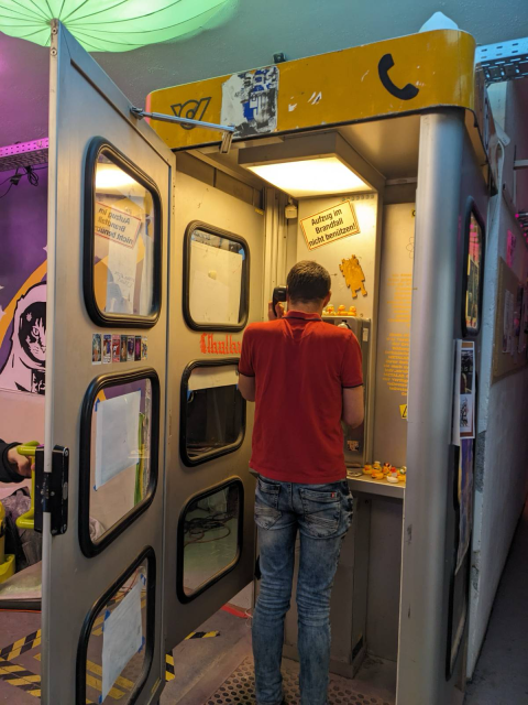 A photo of me standing inside a phone booth with the receiver put to my ear and one of my hands on the keypad.