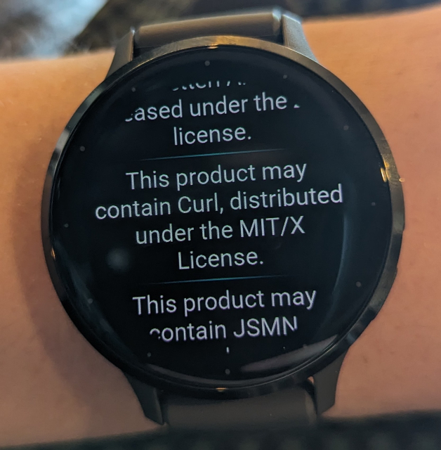 A photo of a Garmin smartwatch on my wrist. It's showing the mandatory list of open source stuff and licenses, which I found deep in some menu. The centered text says: this product may contain Curl, distributed under the MIT/X license.