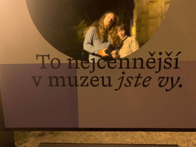 Dva lidi si delaji selfie pred zrcadlem ve velmi spatnem svetle. Pres fotku je napis: "To nejcennejsi v muzeu jste vy."