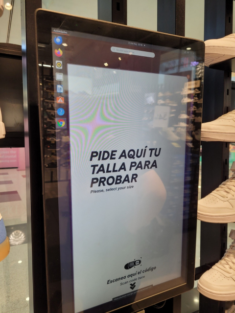 Vertical screen in a sneaker shop showing the GNOME Shell overview interface and a window asking to scan an item and select a size