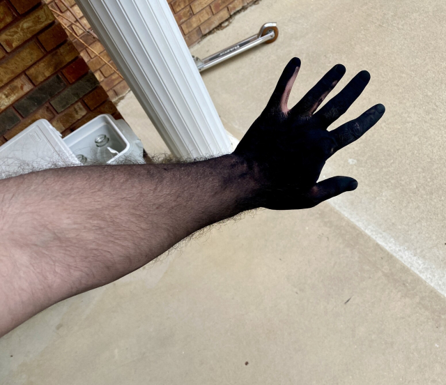 My left hand, almost entirely coated in matte black toner. There’s an ombré effect as there’s less toner further up my arm. 