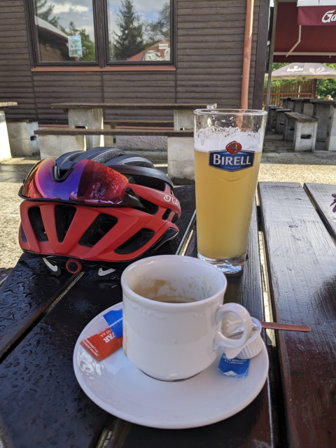 Na obrázku je káva, cyklistická přilba a půlitr Birella Pomelo.