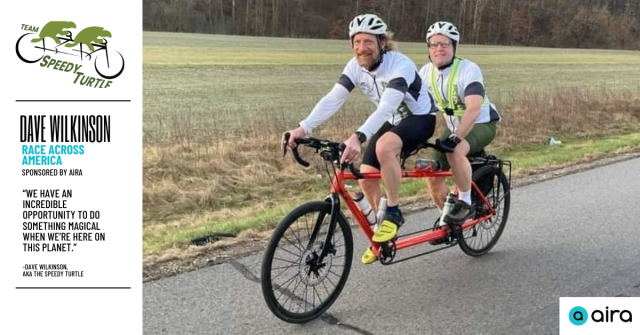 2 men riding a tandem bike along a wooded road wearing white jerseys. Left aligned text reads “Dave Wilkinson, race across America, sponsored by Aira. Below, a quote by Dave reads, “We have an incredible opportunity to do something magical while we’re here on this planet” 
