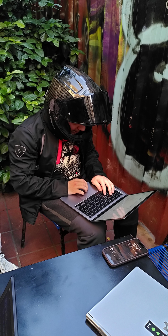 A picture of Jordan wearing his not cool motorbike outfit and helmet.

He is hacking on an Apple M1 laptop.