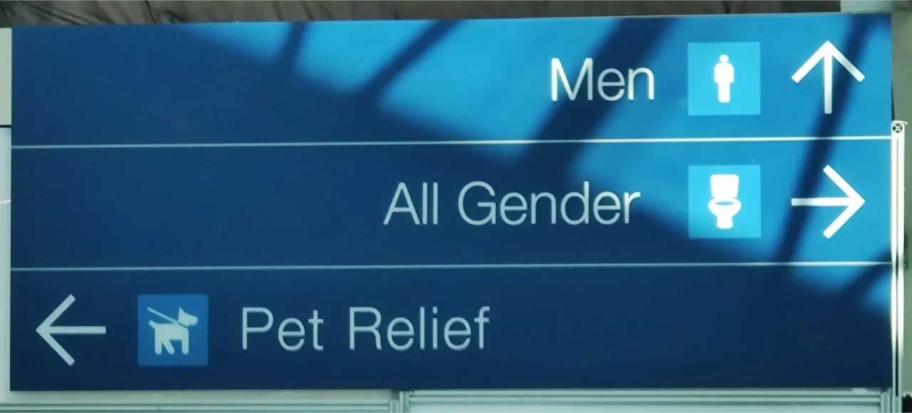 A sign giving directions to toilets for "Men", "All Gender", and "Pet Relief"
