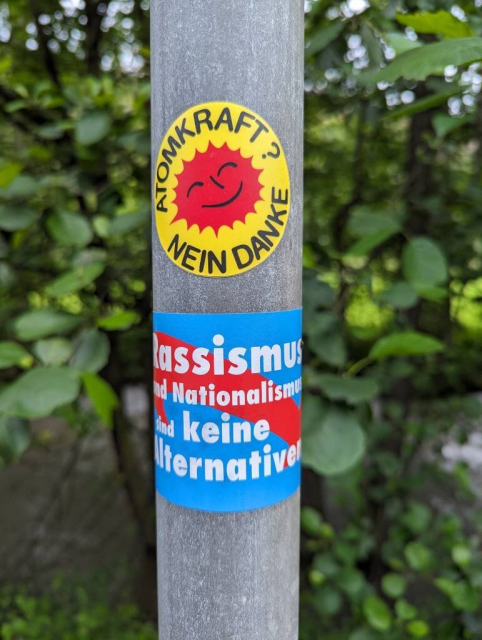 Two stickers on a pillar. 
The first yellow one with this text:
Atom power - no thanks. 
The second, blue with a arrow in down direction:
Racism and Nationalism are no alternatives.