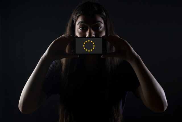 Girl covering her mouth with a phone displaying the EU stars. 