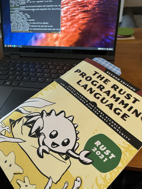 The rust programming language book on top of a laptop keyboard 