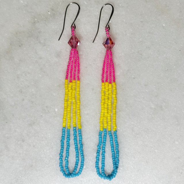 A pair of beaded loop earrings in the pansexual pride colors (pink, yellow, and blue) on a marble background
