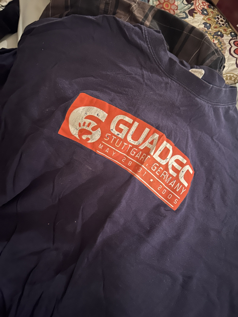 Picture of a navy blue T-shirt with the logo of GUADEC 6 in orange.